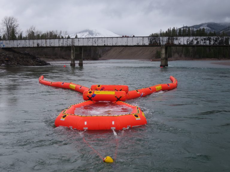 Equipment in the river work to remove oil from spill.