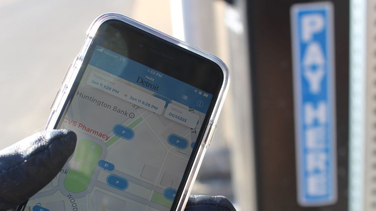 Person holds ParkDetroit App in front of meter.