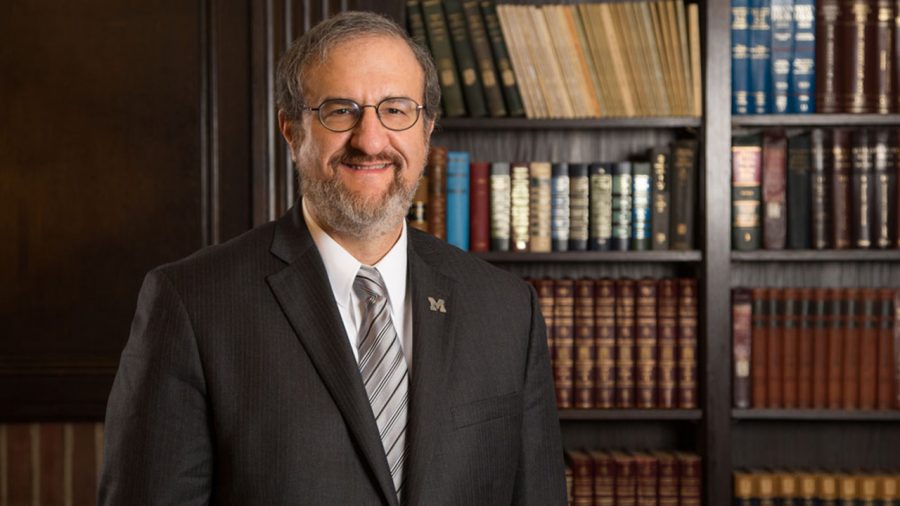 Former U-M President Mark Schlissel stands in front of bookcase.