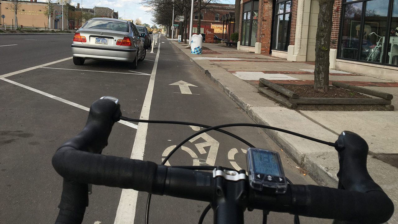 A view of a street with a bike lane from handlebars