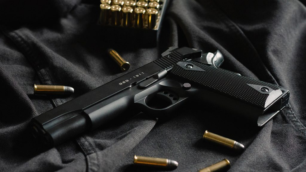 A black revolver on black cloth, with ammunition