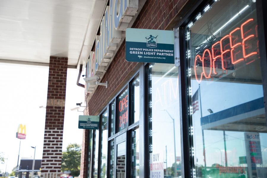 A sign for Detroit's Project Green Light program hangs outside of a gas station.