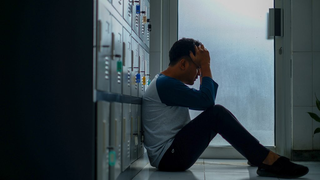 sad student sitting by lockers