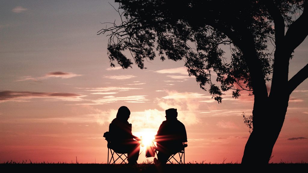 couple sitting by tree sunset