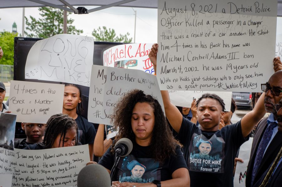 Friends and family of Michael Adams hold up signs