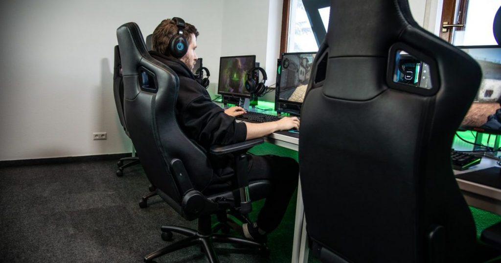 Person sitting in gaming chair at computer with headphones on.