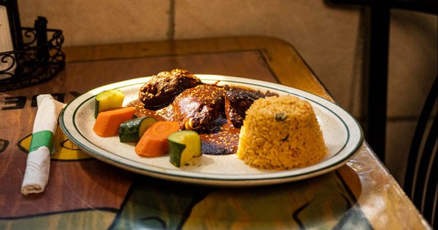 Plated vegetables, rice and mole on a restaurant table.