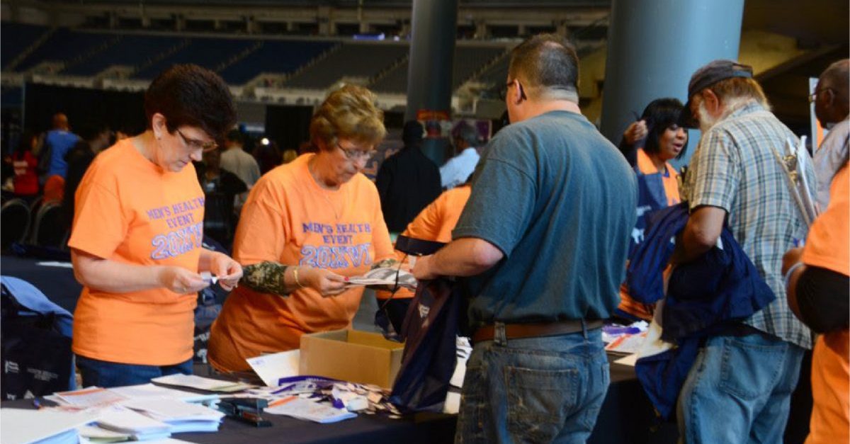 women in matching orange t-shirts sign men into the men's health event