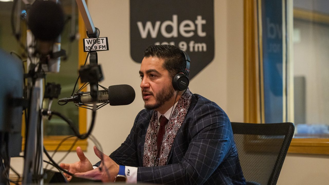 Dr Abdul El-Sayed speaks into a microphone in front of the WDET logo