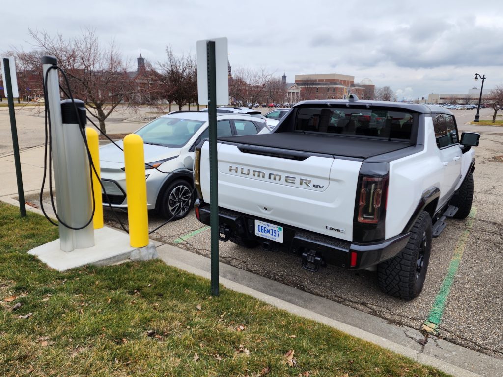 White EV Hummer charges in a parking lot.