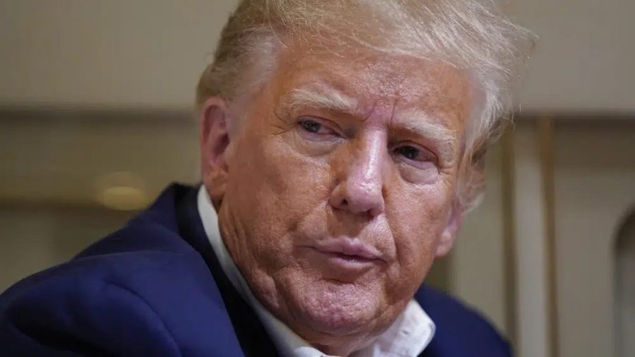 Former President Donald Trump listens as he speaks with reporters while in flight on his plane after a campaign rally at Waco Regional Airport, in Waco, Texas, Saturday, March 25, 2023, while en route to West Palm Beach, Fla.