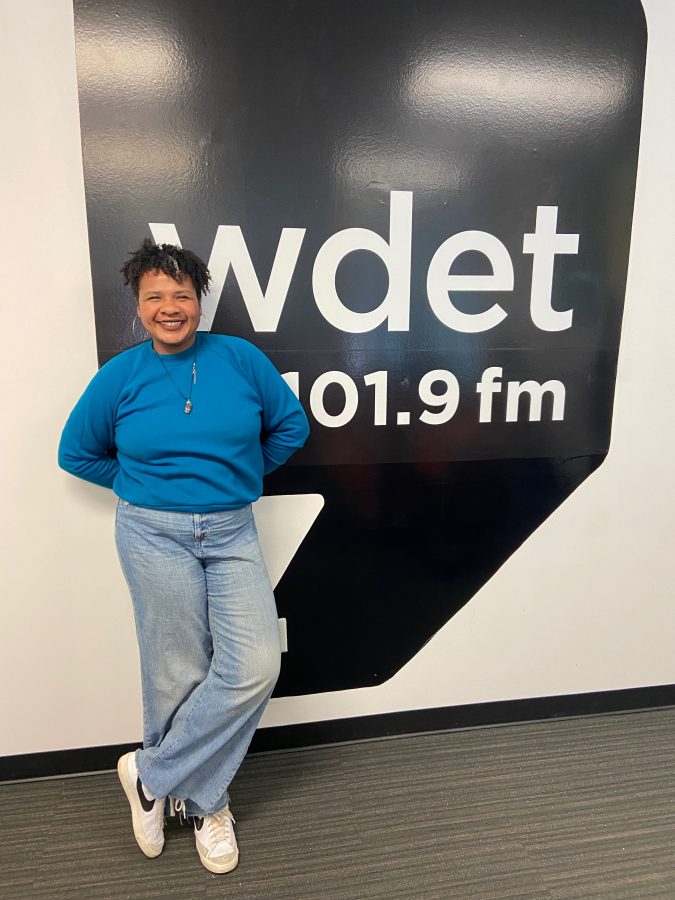 Dr. Jessica Moorman smiles in front of the WDET logo