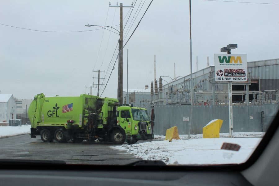 A green garbage truck pulls into WM's transfer station on a snowy day.