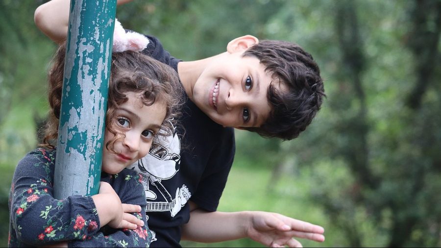 A young pair of siblings plays in a yard