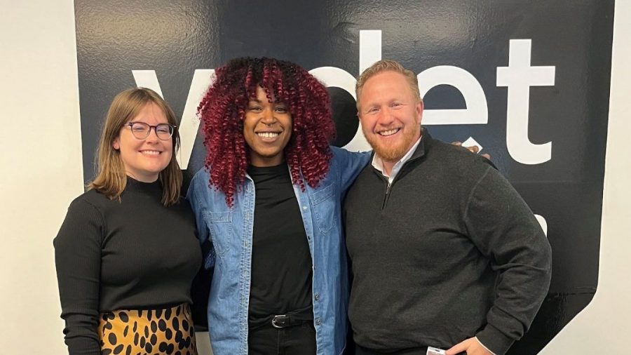 Clare Valenti, Tia Graham and Paul Blatt smile in front of the WDET logo