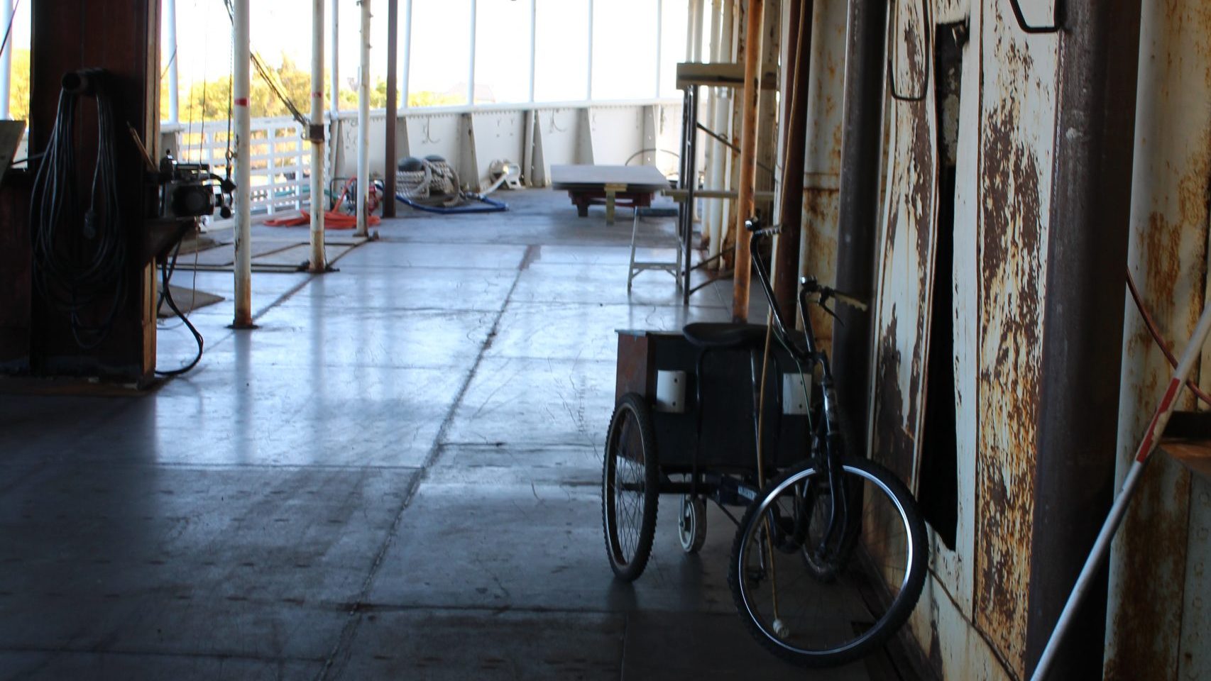 A trike sits next to a rusted wall on the main deck of the Ste. Claire.