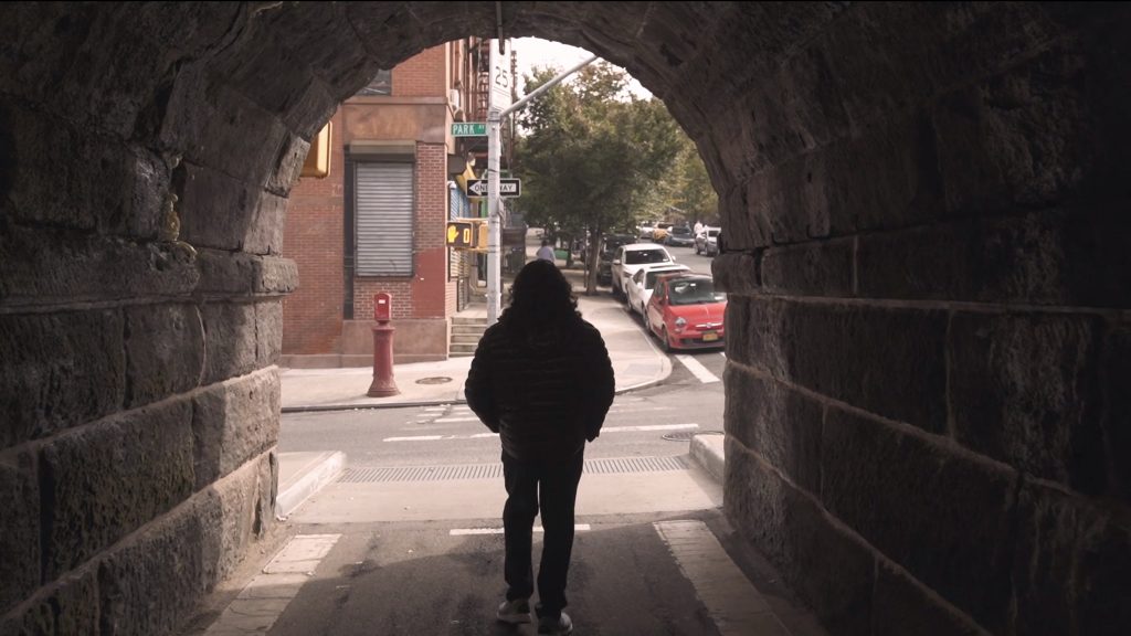 A man walks under a bridge in a city