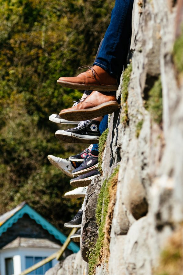 A photo of people's shoes as they're sitting outside.