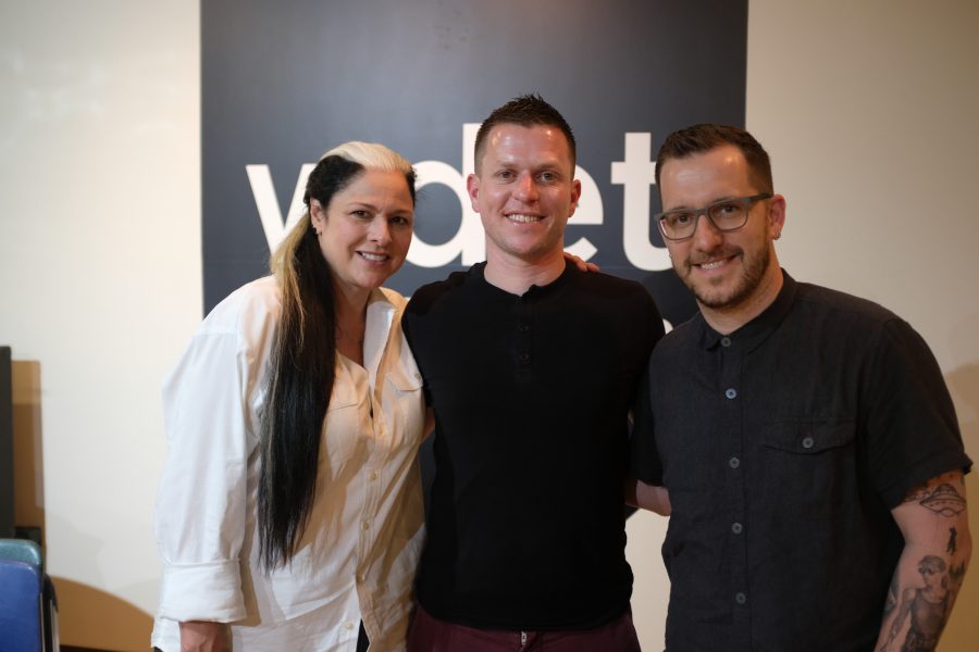 Ann Delisi, John Vermiglio and James Rigato pose in front of the WDET logo.