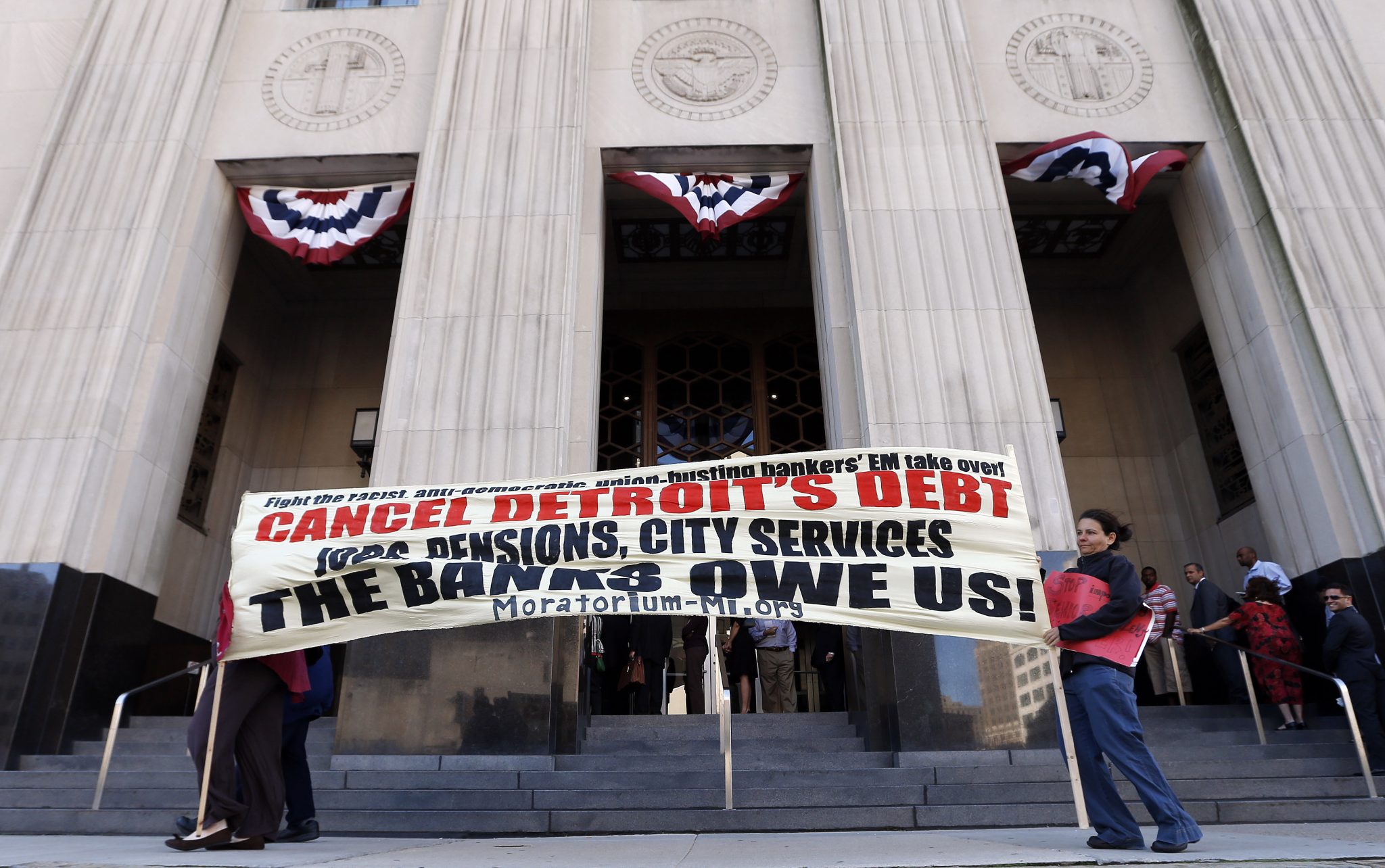 Protesters carry a sign outside the Levin Federal Courthouse in Detroit, Wednesday, July 24, 2013.