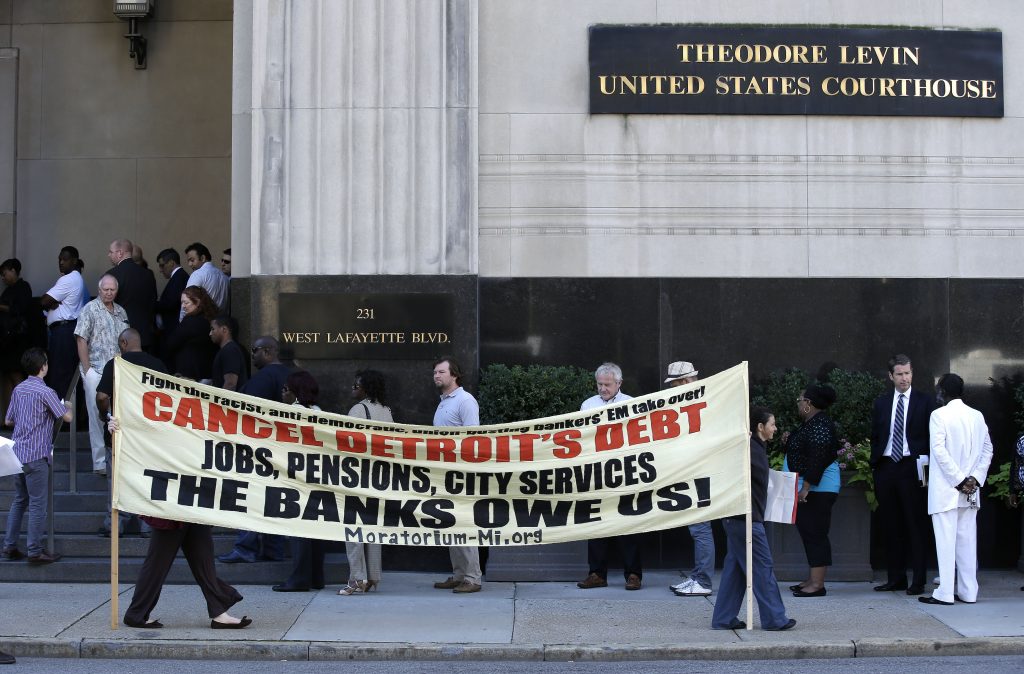 Protesters carry a sign outside the Levin Federal Courthouse in Detroit, Wednesday, July 24, 2013.