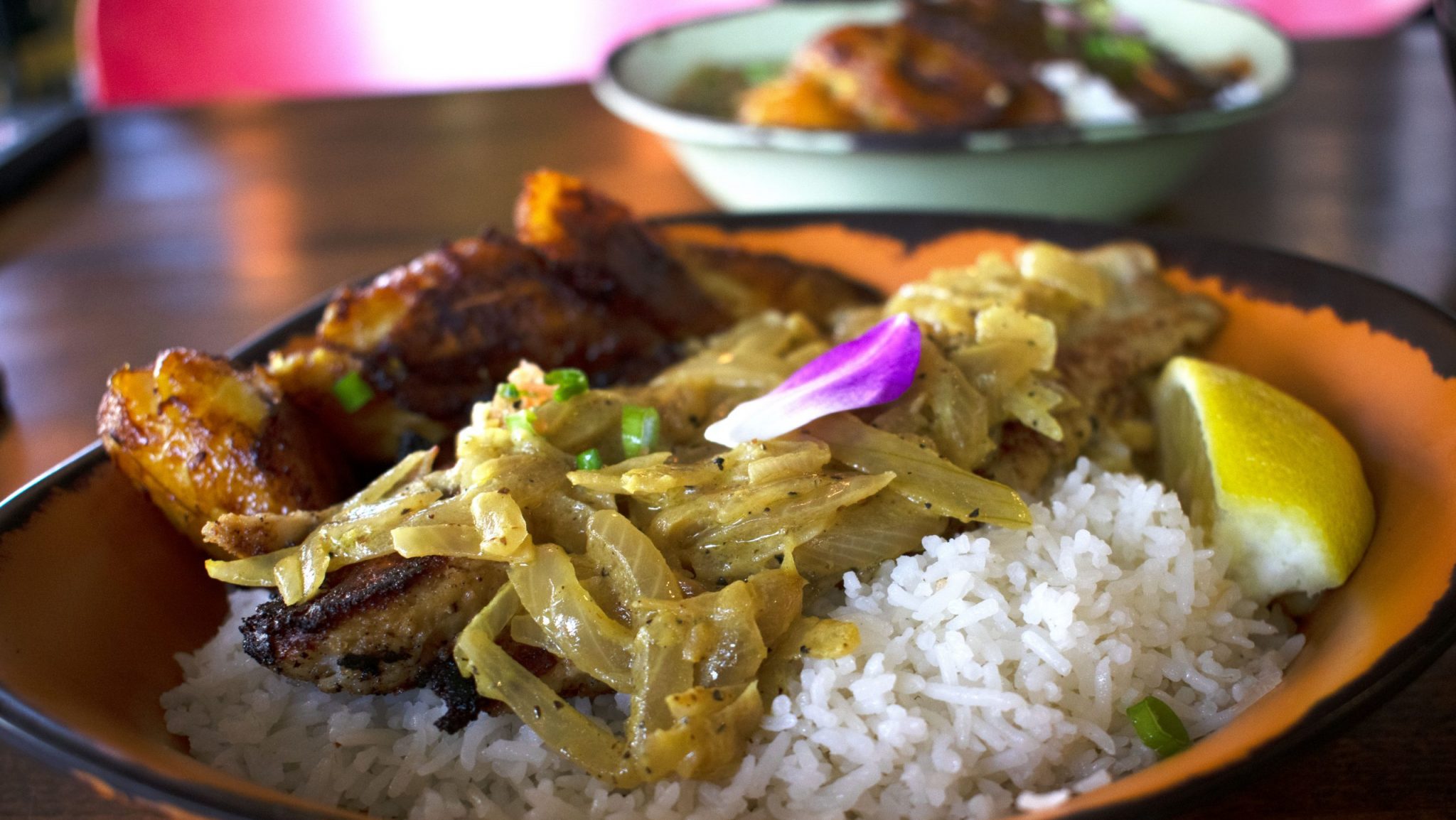 A dish of rice, fish and vegetables garnished with flowers and lemon