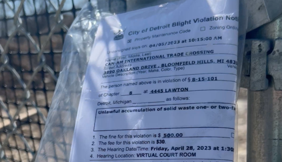 A blight violation from the City of Detroit hangs on the fence of the site of a proposed concrete crusher in Detroit's Core City neighborhood.