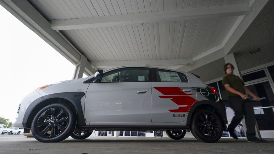 Mitsubishi sales person Matthew Boston walks past a new Mitsubishi Mirage for sale at El Cajon Mitsubishi on Tuesday, Aug. 8, 2023, in El Cajon, Calif.