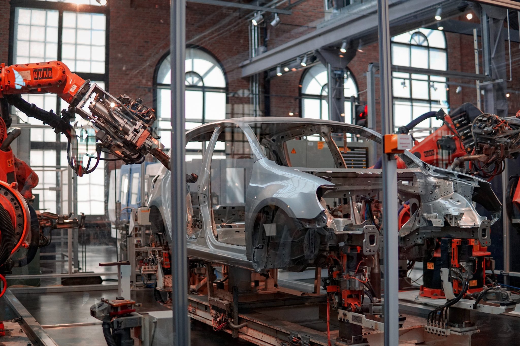 Gray vehicle being fixed inside a building using robot machines.