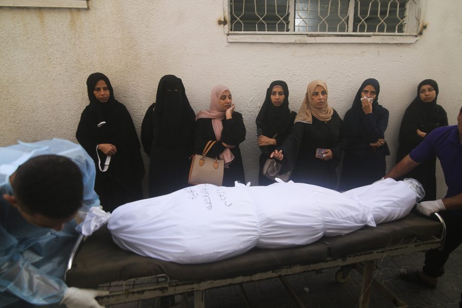 Palestinian women stand next to the body of a person killed in the Israeli bombing of the Gaza Strip in Rafah on Tuesday, Oct. 24, 2023.