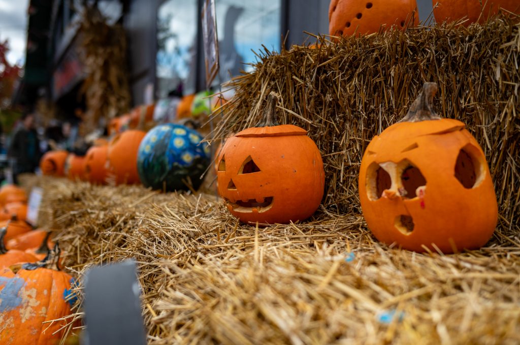 Halloween craved pumpkins atop hay bales.