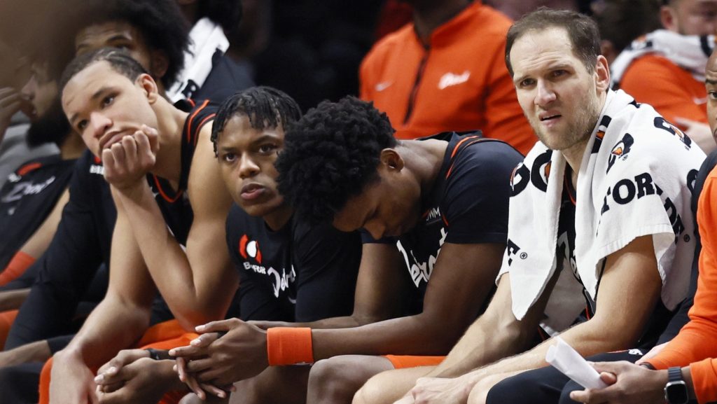 Detroit Pistons players sit disappointed on the bench at a game.