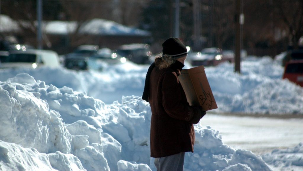 Homeless woman holds sign during winter