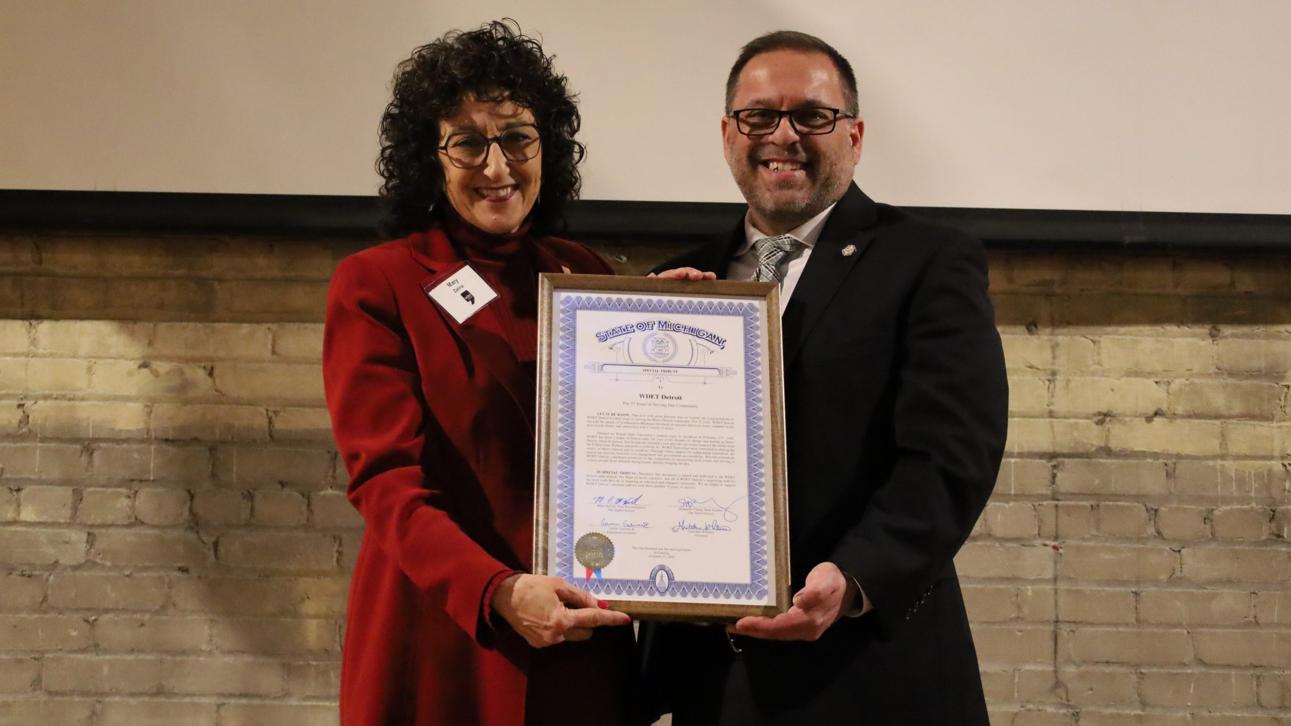 WDET General Manager Mary Zatina accepts a special recognition plaque from Michigan State Rep. Mike McFall during WDET's 75h anniversary party on Feb. 13, 2024, at the Jam Handy in Detroit.