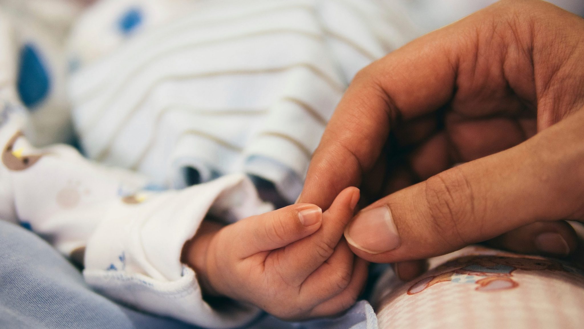 Mother holding the hands of a new born baby.