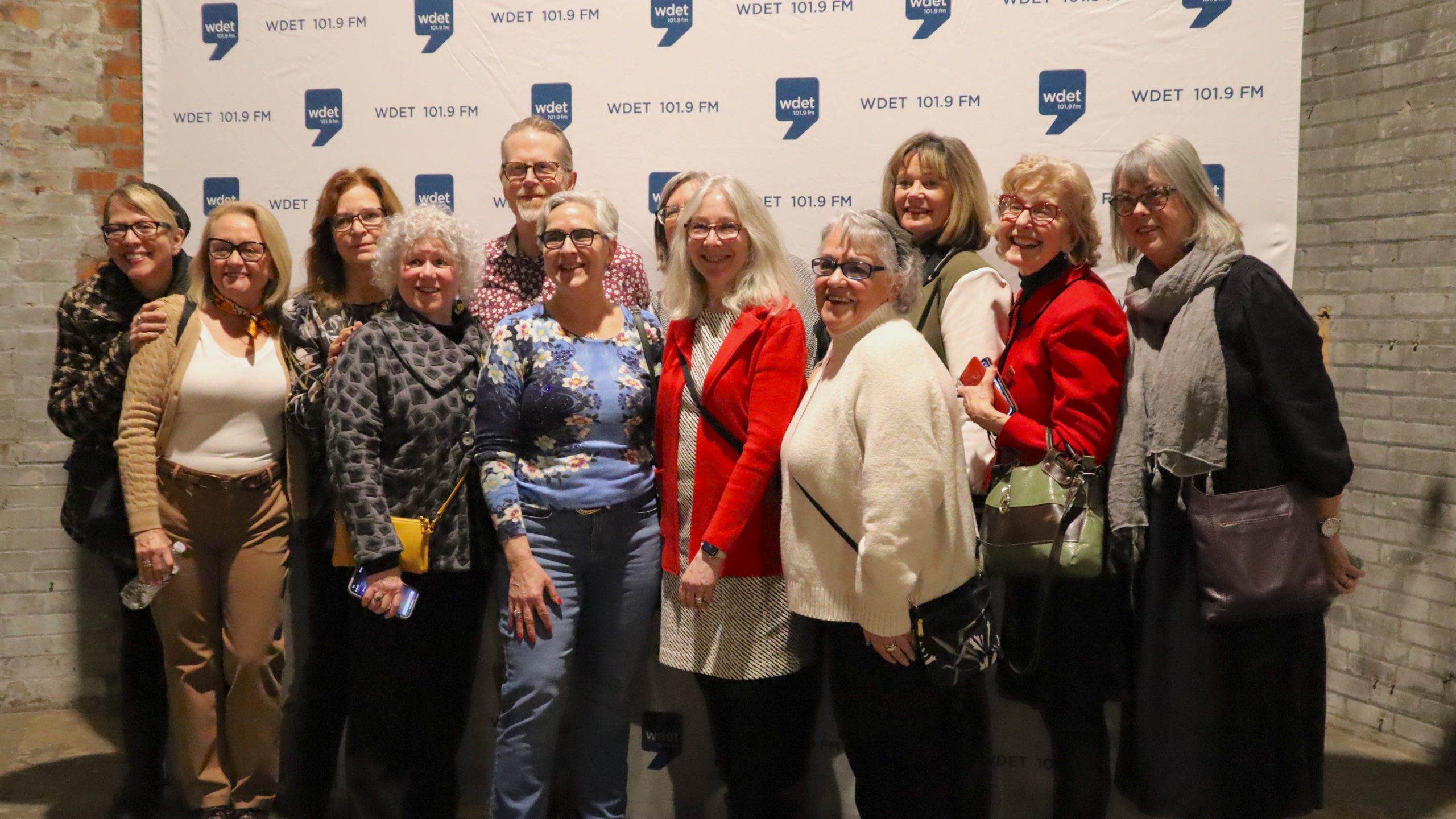 Guests pose in front of a WDET banner.