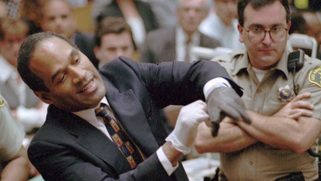 FILE - In this June 15, 1995 file photo, O.J. Simpson, left, grimaces as he tries on one of the leather gloves prosecutors say he wore the night his ex-wife Nicole Brown Simpson and Ron Goldman were murdered in a Los Angeles courtroom. Simpson, the decorated football superstar and Hollywood actor who was acquitted of charges he killed his former wife and her friend but later found liable in a separate civil trial, has died. He was 76.