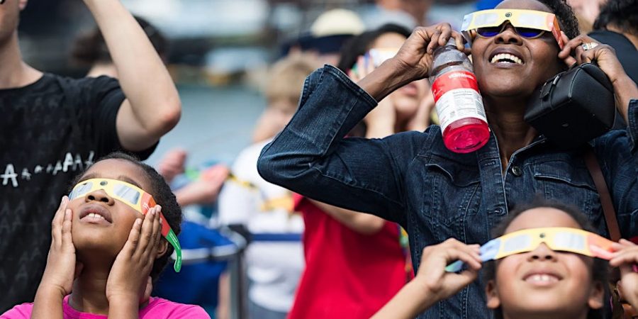 Families watch an eclipse through eclipse glasses