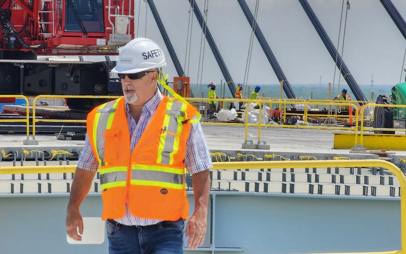 A worker on the Detroit side of the international span, with a Canadian construction crew separated by an 85-foot gap.