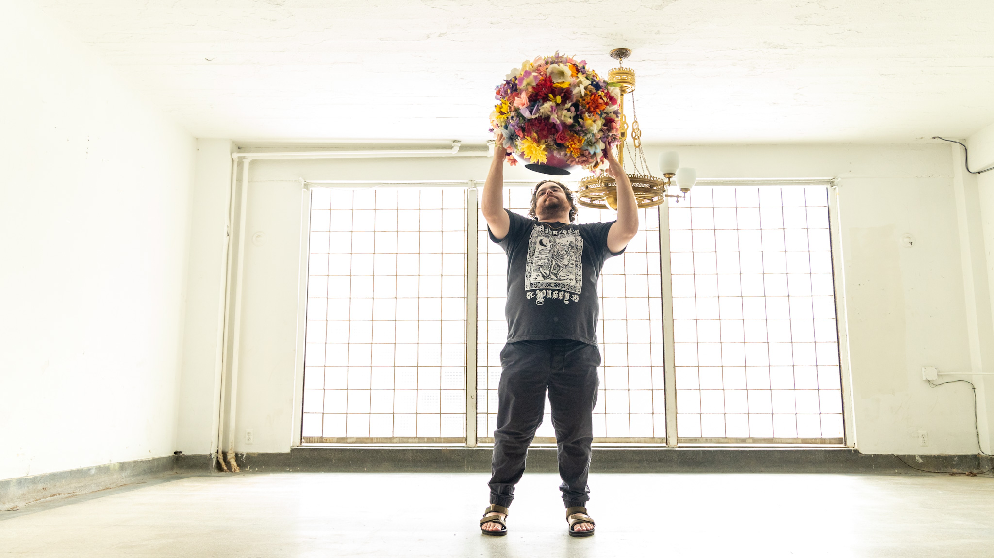 WDET host Ryan Patrick Hooper about to wear a flower headdress created by artist Lisa Waud at her "Portrait" art installation at the Boyer Campbell building in Detroit on June 26, 2024.