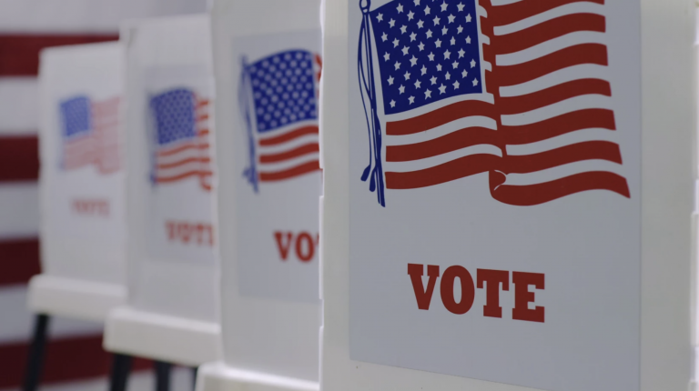 Voting tables with dividers are lined up in a row.