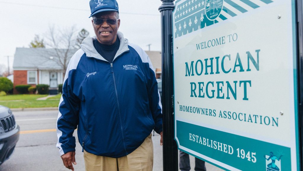 Mohican Regent Community Association President George Preston proudly stands in front of his neighborhood's new welcome sign.