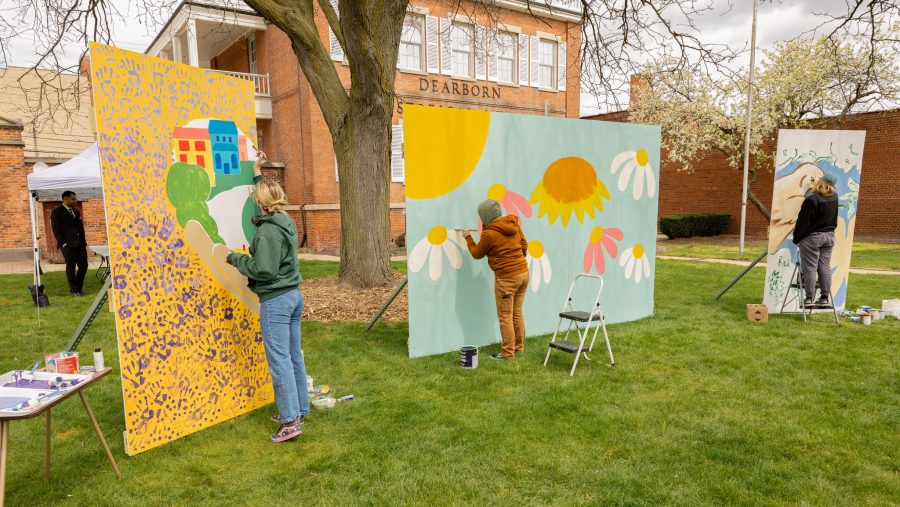 Painters work on large brightly-colored pieces outside