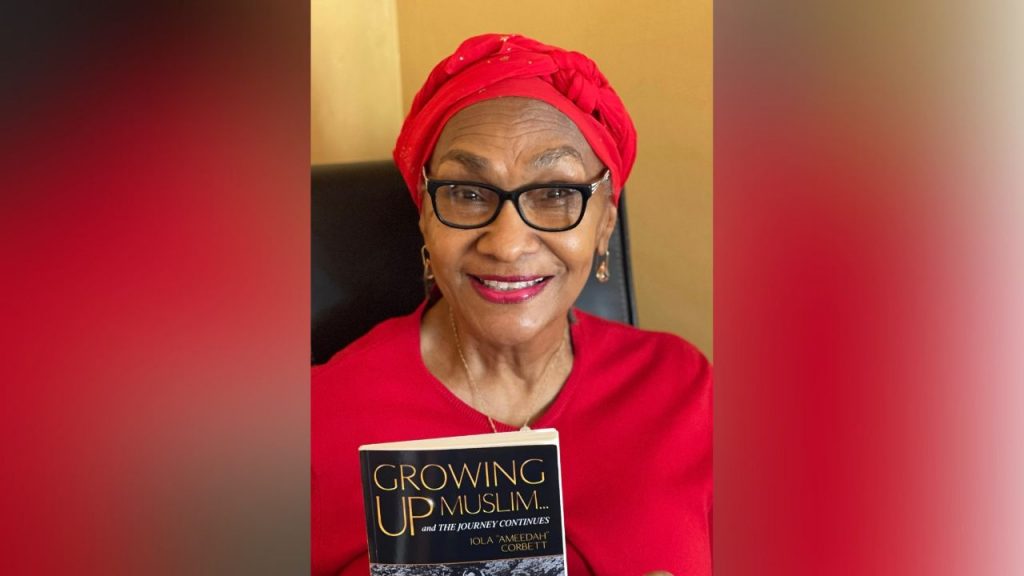Iola Corbett holds up a copy of her book, "Growing Up Muslim"