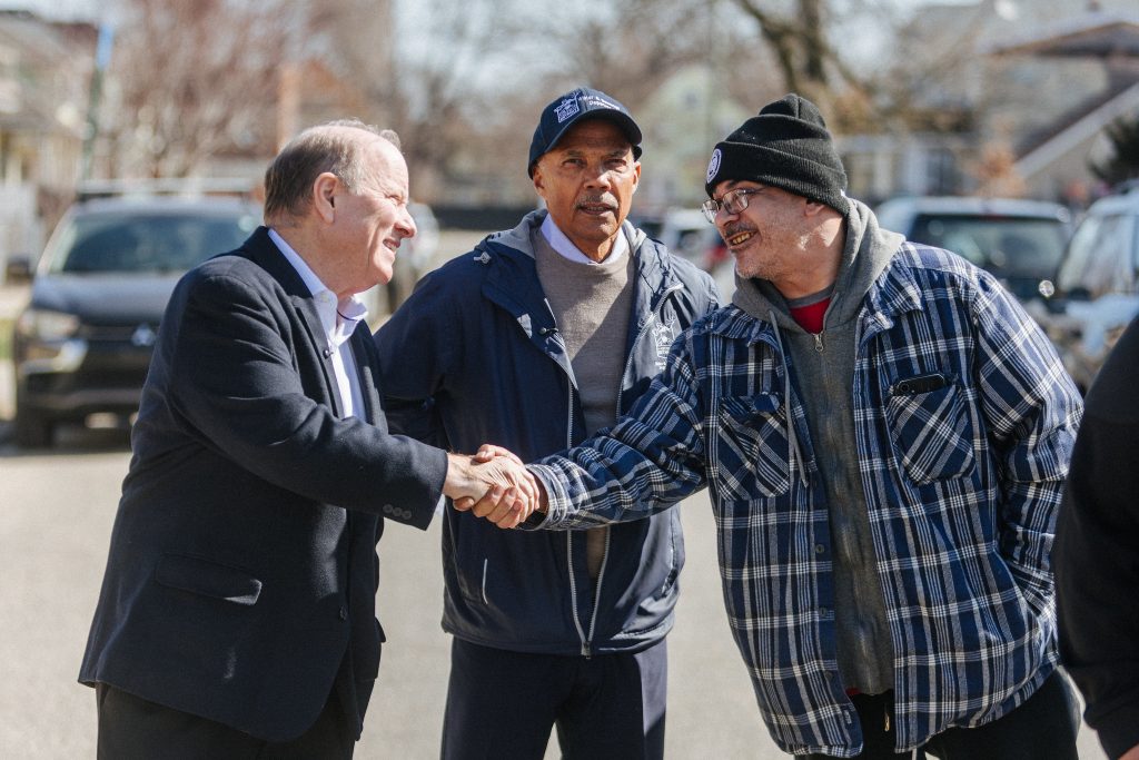 Mike Duggan shakes hands with a resident at a press conference in Southwest Detroit