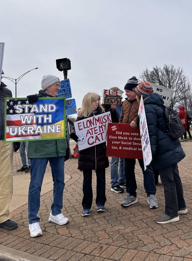 Tesla Takedown protestors demonstrate on the sidewalk outside Somerset Mall in Troy.