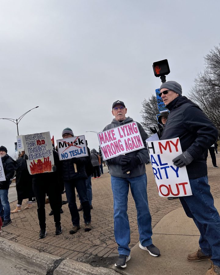 Tesla Takedown protestors demonstrate on the sidewalk outside Somerset Mall in Troy.