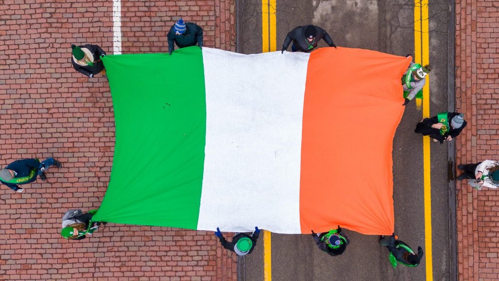 Attendees at Detroit's 2023 St. Patrick's Parade hold an Irish flag.