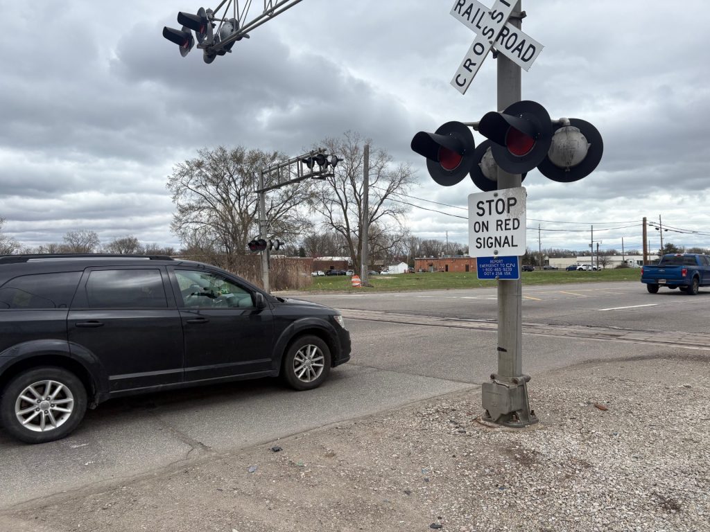 A car sits at a railroad crossing.
