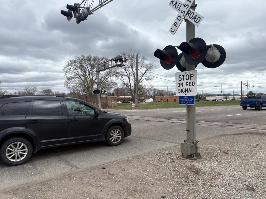 A car sits at a railroad crossing.